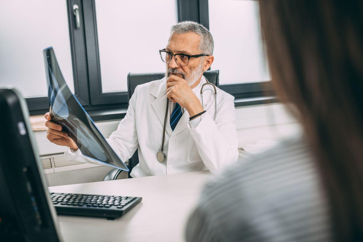 Ein erfahrener Radiologe in der Radiologie Köln betrachtet eine Röntgenaufnahme und bespricht die Diagnose mit einer Patientin.