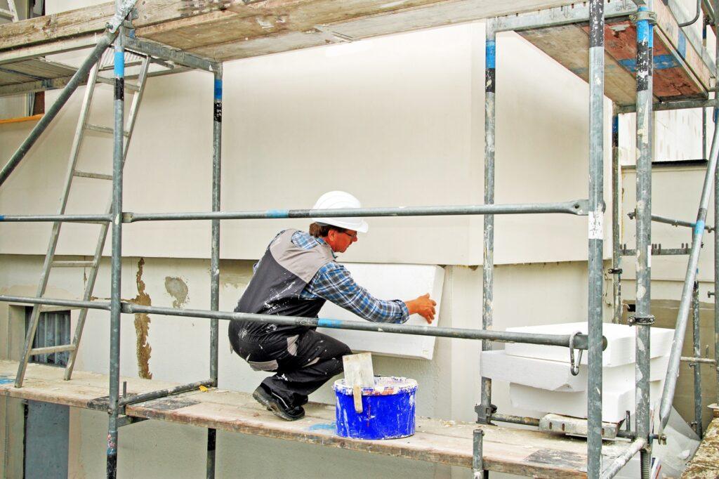 Handwerker bringt Styroporplatten an der Hausfassade an