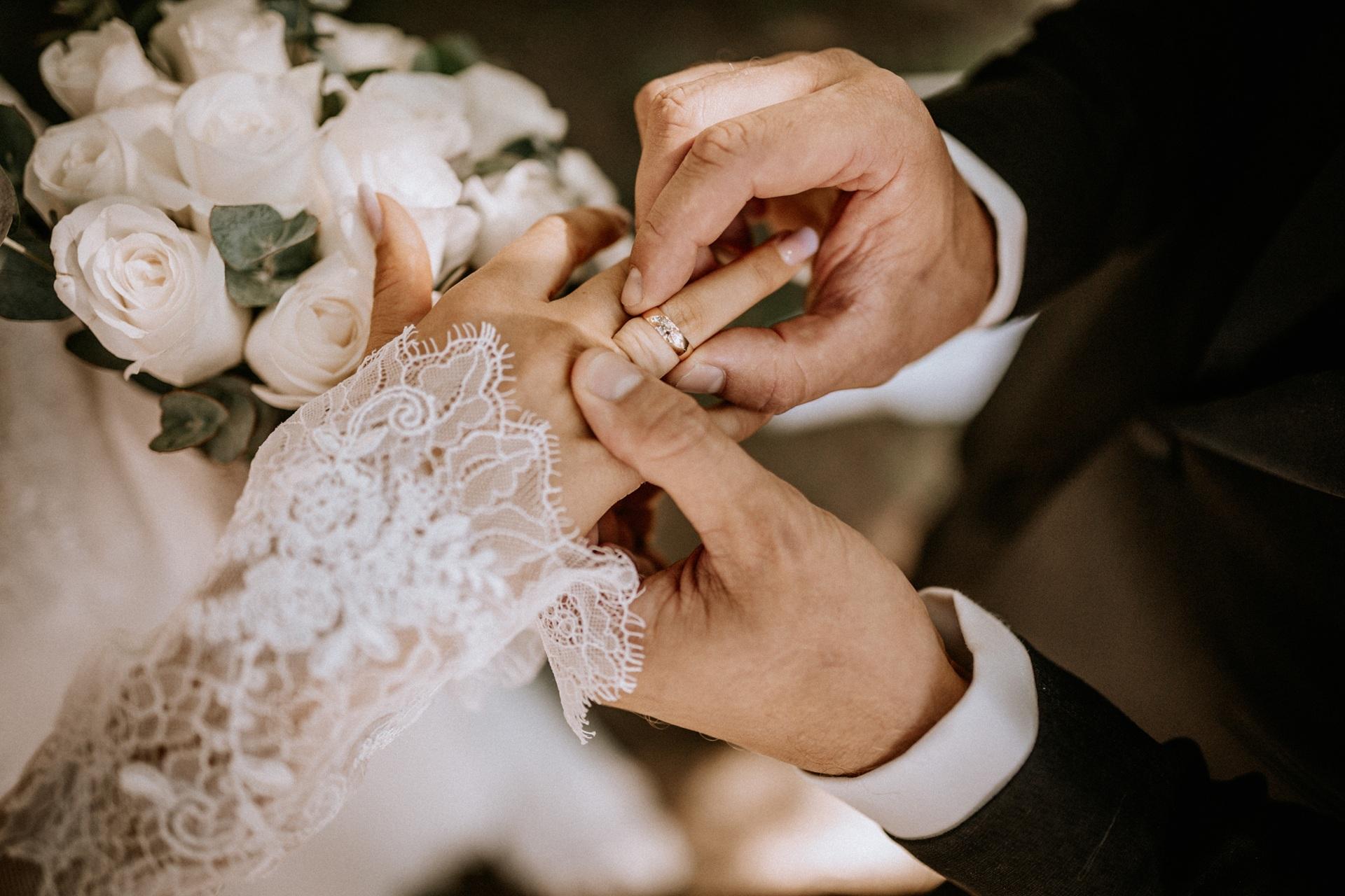 Hand mit Spitze beim Anstecken des Rings | Brautmode Kiel

