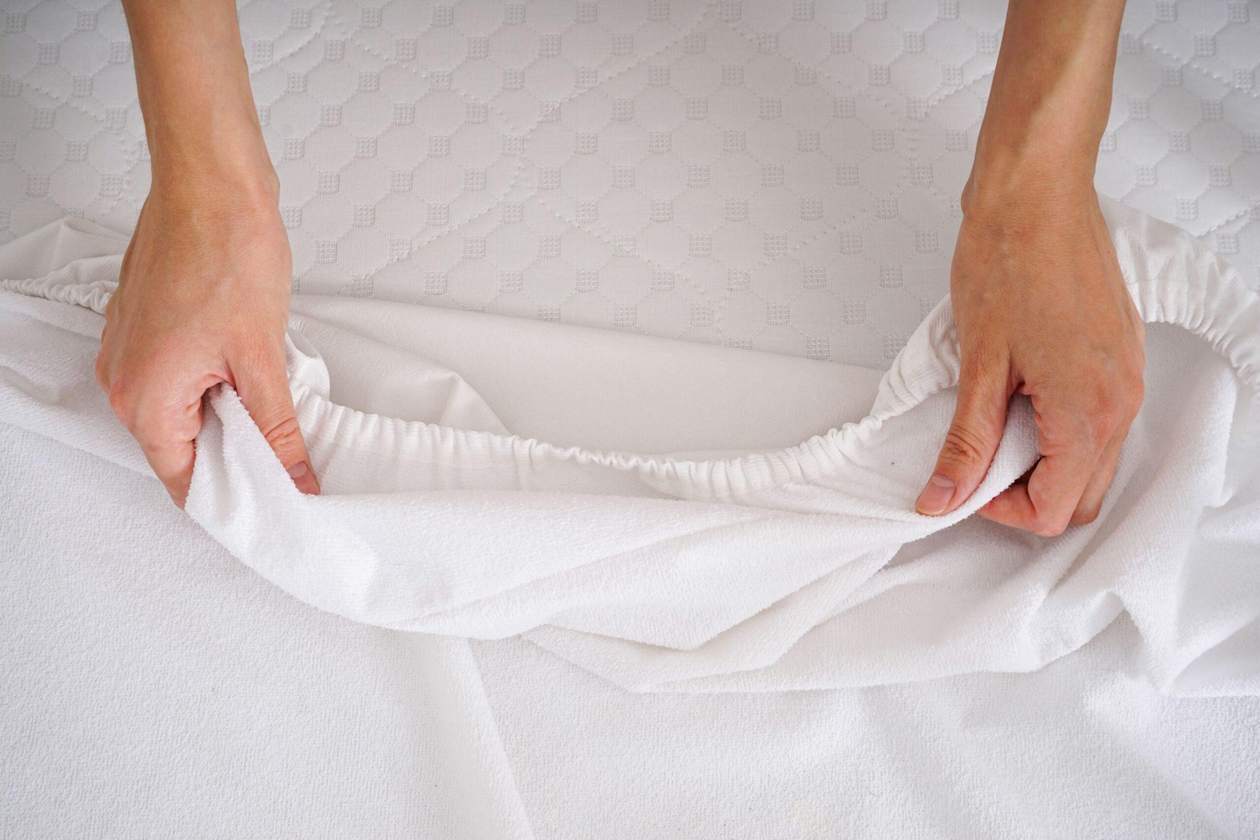 Hände prüfen die Spannkraft eines weißen Spannbettlakens 160x200 – Fokus auf Material und Qualität