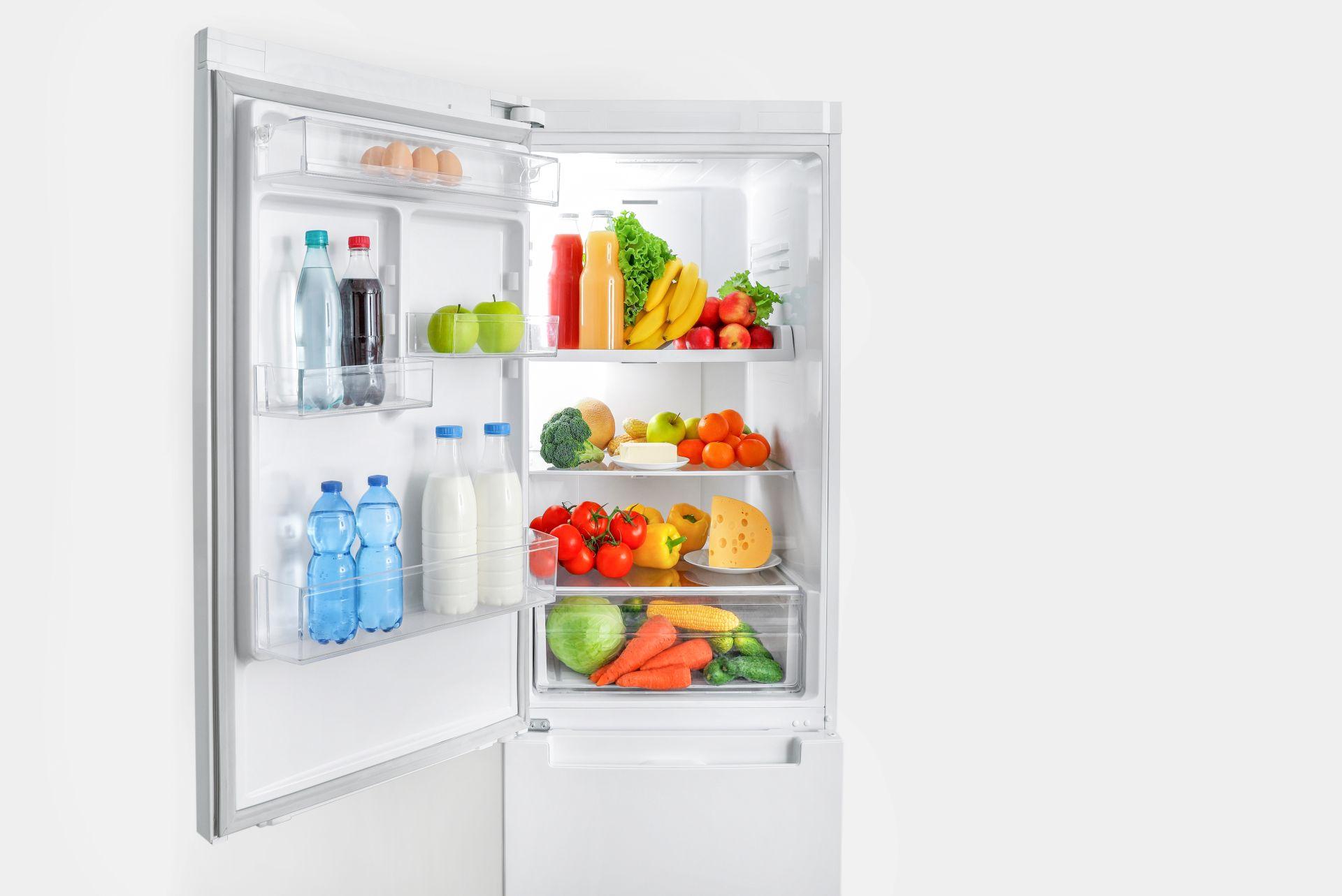 Geöffneter Kühlschrank mit Wasserflaschen und frischem Gemüse