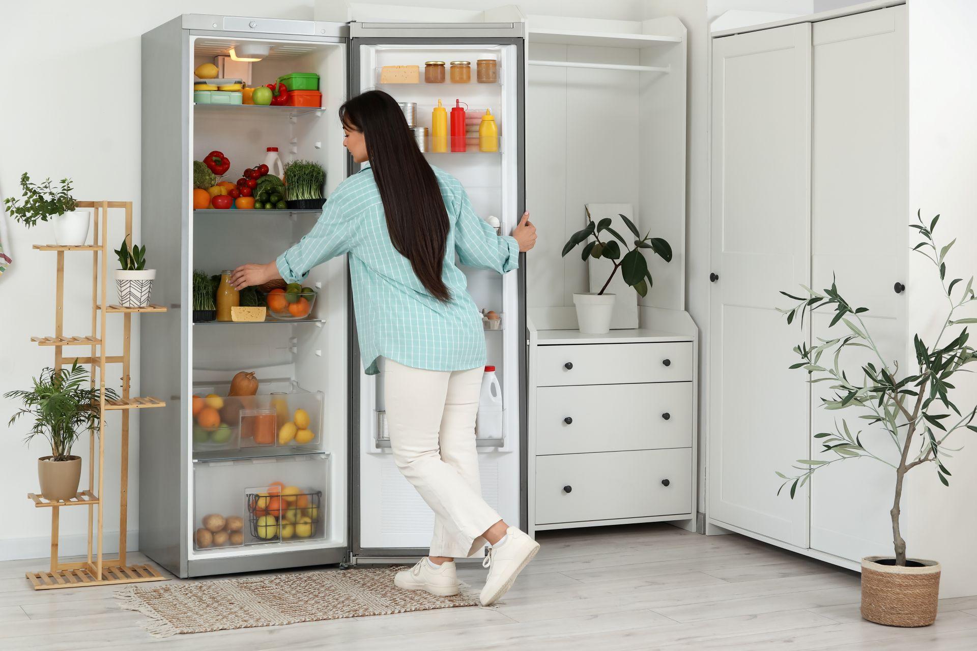 Frau öffnet Kühlschrank in heller Küche