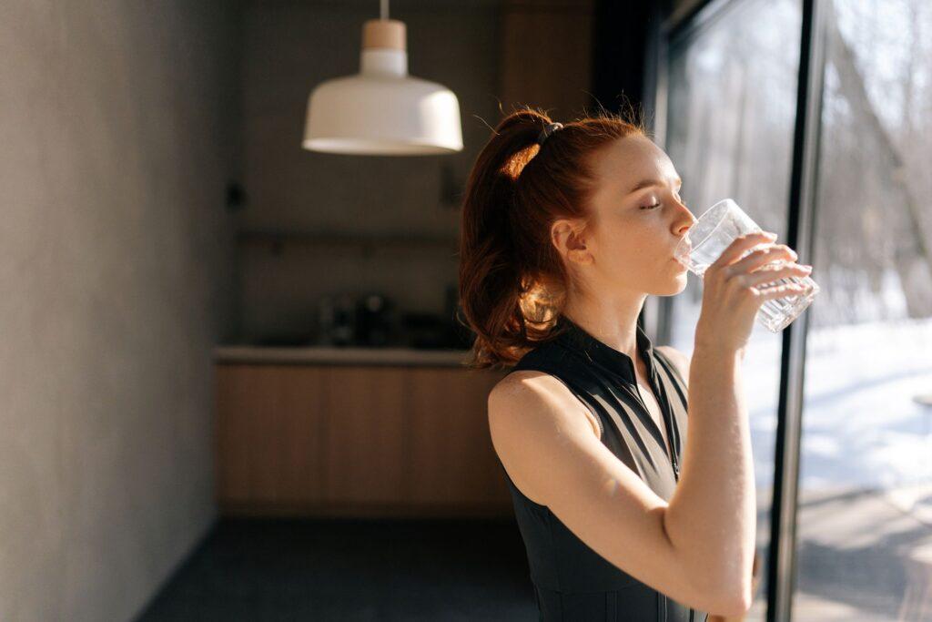 Junge Frau trinkt Wasser im Morgenlicht